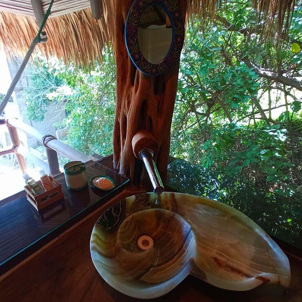 A wooden table with a glass bowl, a candle, and a small container.