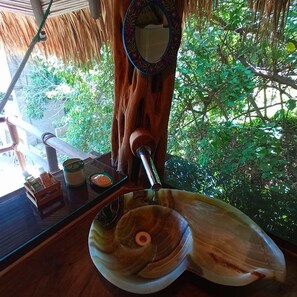 A wooden table with a glass bowl, a candle, and a small container. - Zazil Retreat (Santa María Tonameca)