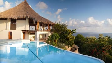 Piscina com um edifício de telhado de palha ao fundo.