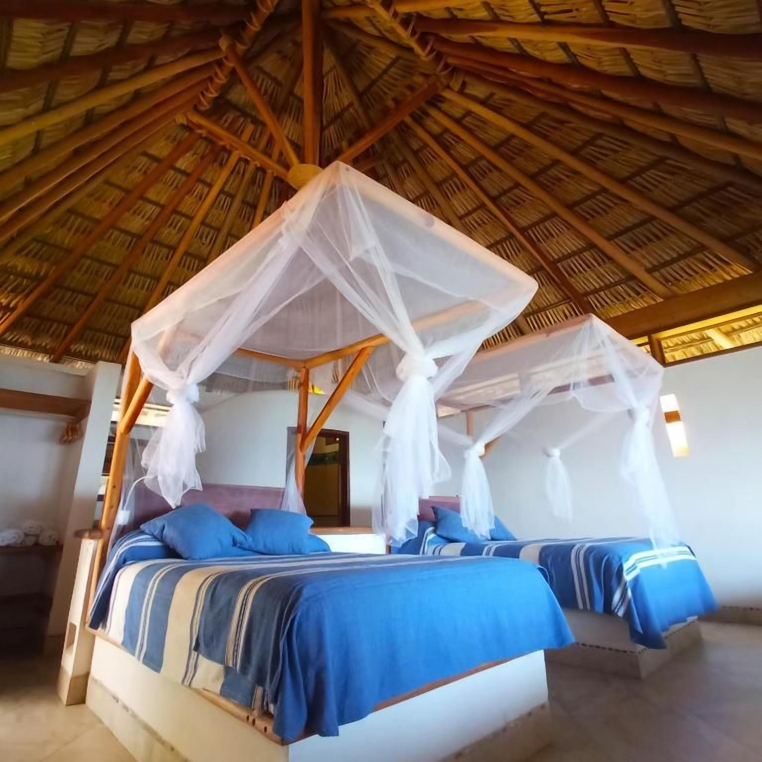 Quarto com telhado de palha, cama com dossel e janela.