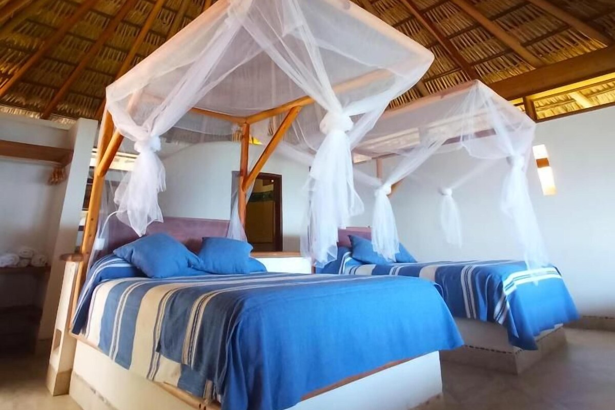 A room with a thatched roof, a bed with a canopy, and a window.