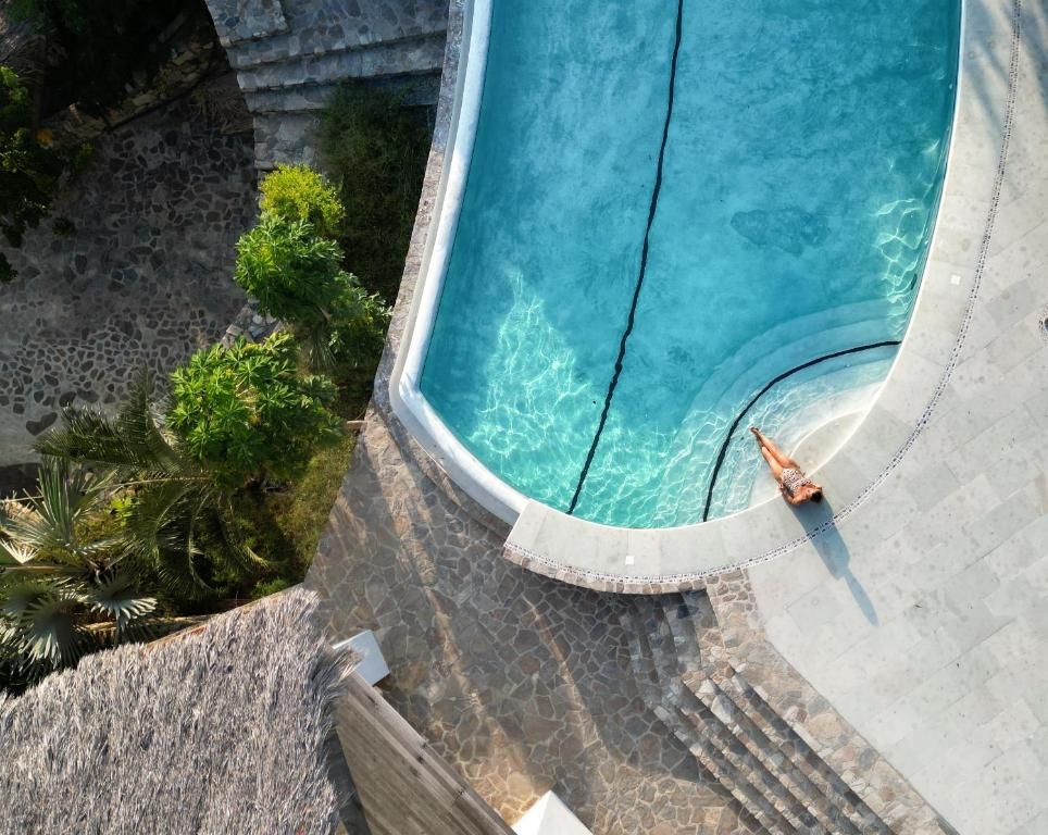 Vista aérea de uma piscina com água cristalina, rodeada por degraus de pedra e vegetação.