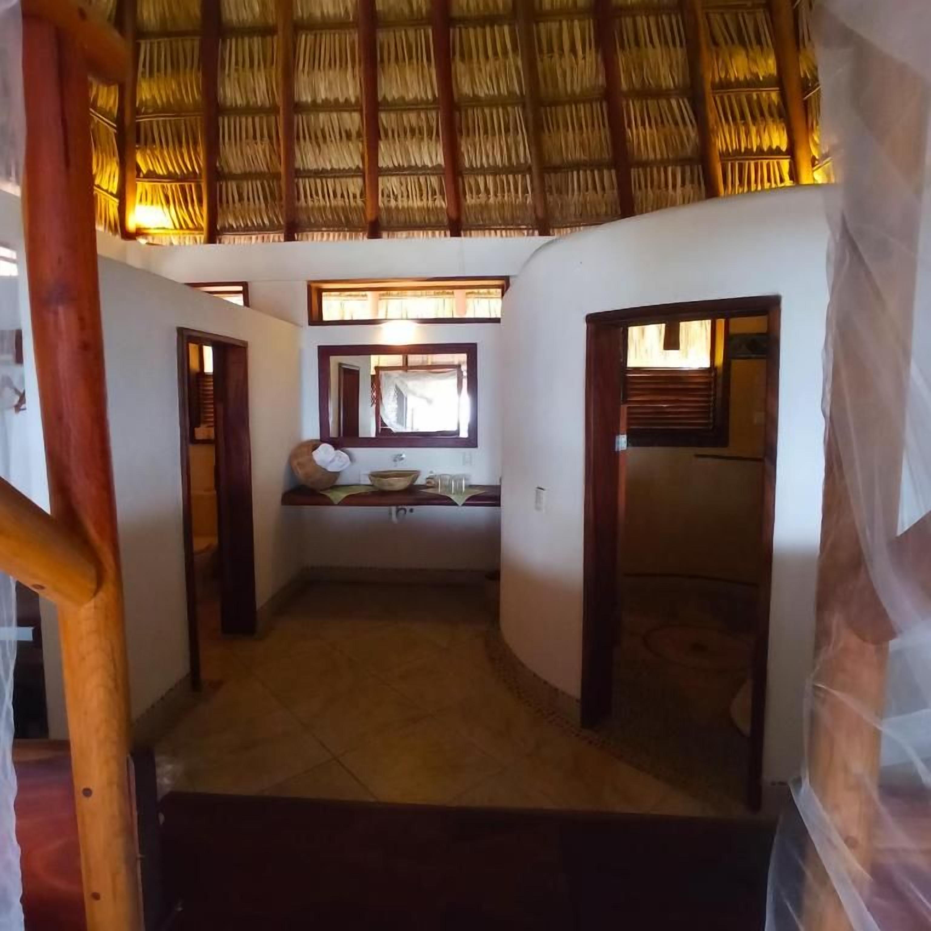 Ein Korridor mit einem Reetdach, einem kleinen Fenster mit Blick und einem Spiegel an der Wand.
