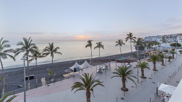A coastal promenade with palm trees, a beach, and buildings in the background. - Studio 'Martin - 30' with Sea View, Balcony and Wi-Fi (Puerto de Naos)