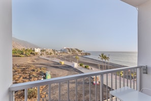 A balcony with a view of a beach, buildings, and a clear sky.