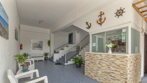 A reception area with a stone counter, white wicker furniture, a staircase, and nautical decor. - Studio 'Martin - 30' with Sea View, Balcony and Wi-Fi (Puerto de Naos)
