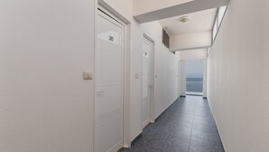 A narrow hallway with white doors, a tiled floor, and a view of the sea through a balcony. - Studio 'Martin - 30' with Sea View, Balcony and Wi-Fi (Puerto de Naos)