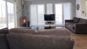 Una sala de estar moderna con chimenea, un televisor de pantalla plana y un sofá seccional marrón.
