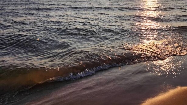 Ein Strand mit der Sonne, die sich im Wasser spiegelt.