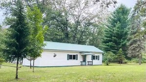 Ein Bungalow mit Gründach, umgeben von einem Rasen und hohen Bäumen.