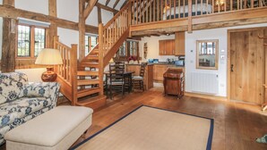 A spacious loft with a wooden staircase, a dining area, and a kitchen.