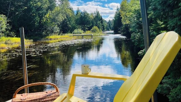 A river view with a chair and a basket, surrounded by greenery and trees. - Chalet - Waterfront haven A host of activities for all seasons (Chertsey)