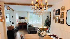 A dining area with a wooden table, chairs, a chandelier, and a Christmas tree. - Chalet - Waterfront haven A host of activities for all seasons (Chertsey)