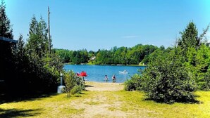 A lakeside path leading to a body of water with boats, surrounded by dense greenery. - Chalet - Waterfront haven A host of activities for all seasons (Chertsey)