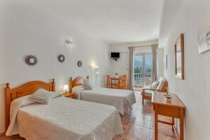 Une chambre d’hôtel avec deux lits, un bureau, une chaise, une télévision et un balcon avec vue.