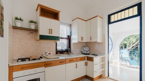 Een keuken met witte kastjes, een fornuis en een raam.