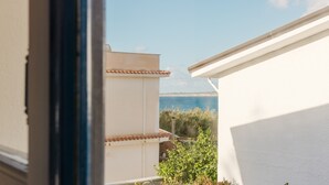 Een balkon met uitzicht op zee, een wit gebouw en een pannendak.