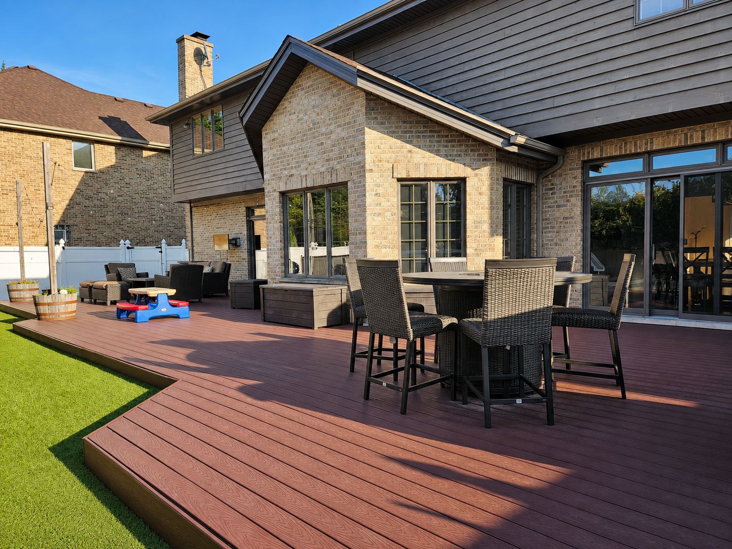 A residential deck with outdoor furniture and a stone facade.