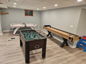 A room with a foosball table, a pool table, and a shuffleboard table. - Fun 5BR 4.5BA, Pool, Hot Tub, Game Rm, Near O’Hare (Wood Dale)