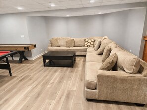 A living room with a pool table, a sectional sofa, and a coffee table.