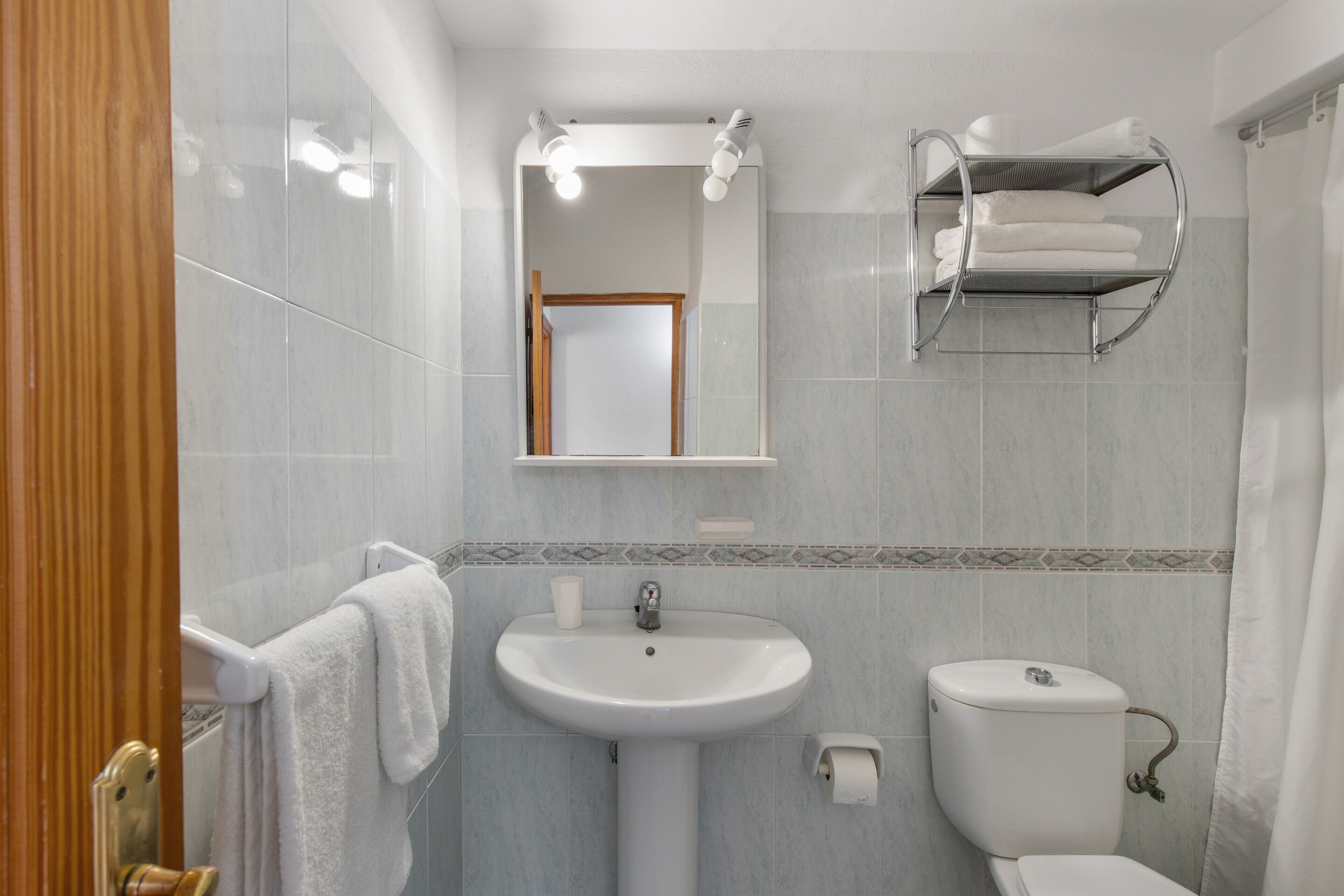 Une salle de bain équipée d’un lavabo, de toilettes, d’un porte-serviettes et d’un miroir.