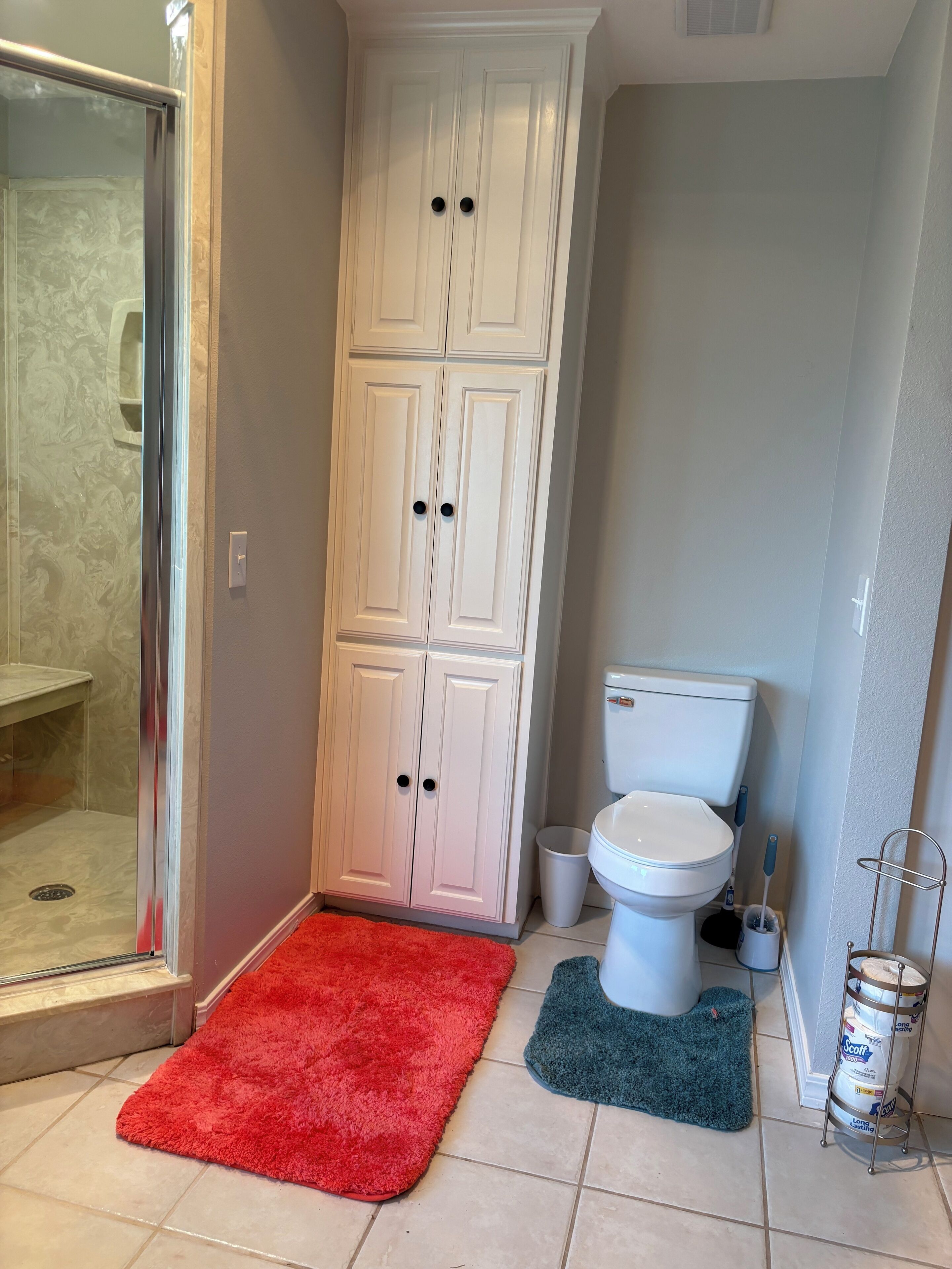 Een badkamer met een inloopdouche, toilet en kast.