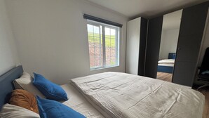 Un dormitorio con cama, almohadas, ventana y armario.