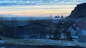 Un pueblo costero con casas, un acantilado rocoso y vistas al mar al atardecer.