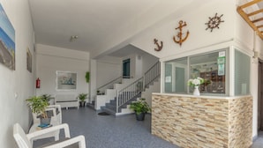 A reception area with a stone counter, white wicker furniture, a staircase, and nautical decor. - Studio 'Martin - 23' with Sea View, Balcony and Wi-Fi (Puerto de Naos)
