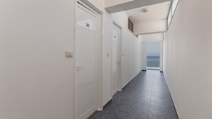 A corridor with white doors, a tiled floor, and a view of the sea through a window. - Studio 'Martin - 23' with Sea View, Balcony and Wi-Fi (Puerto de Naos)