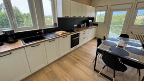 Una cocina moderna con armarios blancos, encimera negra y un comedor con mesa y sillas.