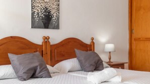 A neatly made bed with a wooden headboard, two pillows, and a white towel.