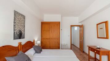 Ein Schlafzimmer mit zwei Betten, einem Holzschrank, einem kleinen Tisch und einem Spiegel.