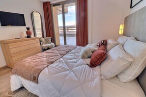 A bedroom with a bed, a dresser, a mirror, and a television.