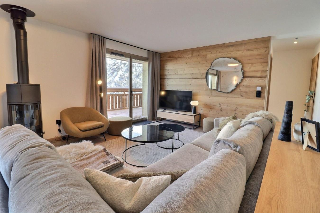 A modern living room with a large sofa, a round coffee table, a TV, and a fireplace.