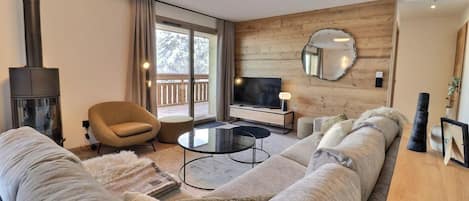 Una sala de estar moderna con un sofá grande, una mesa redonda de centro, un televisor y una chimenea.