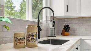 A kitchen with a white countertop, a black faucet, and two beer cans. - New Adventure Cottage w/ Mountain Views Near Garden of the God's and much more! (Colorado Springs)