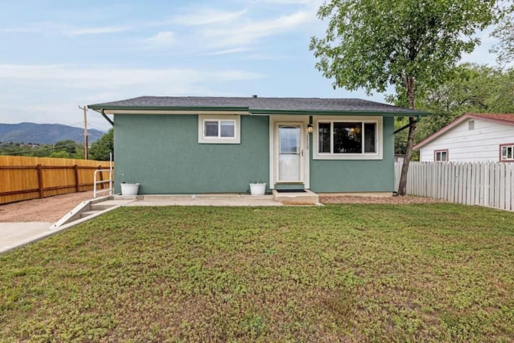 A single-story house with a green exterior, a front door, and a small porch.