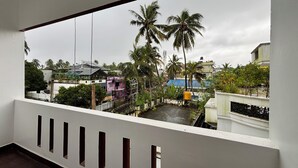 A balcony with a view of a residential area, including houses and palm trees. - Fort Grande Stay  (Kochi)