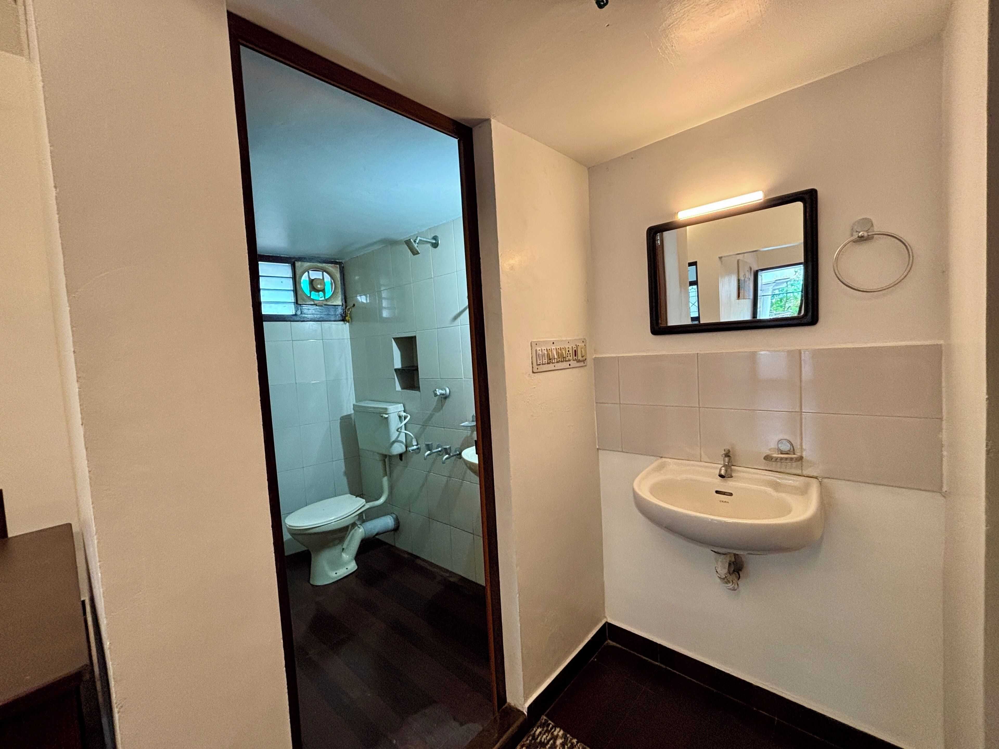 A bathroom with a toilet, sink, and mirror.