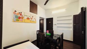 Quarto com mesa de jantar, cadeiras, ventilador de teto e parede com um mural colorido.