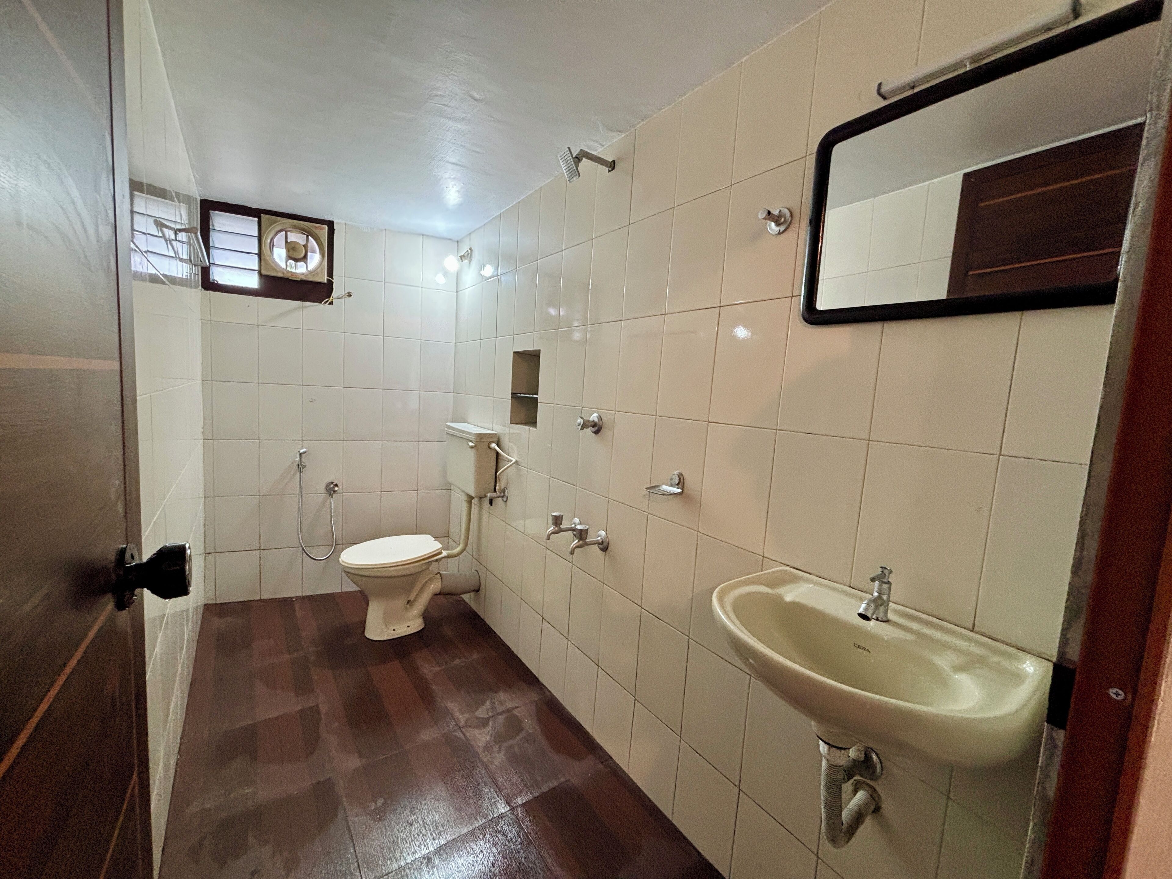 A bathroom with a toilet, sink, and mirror.