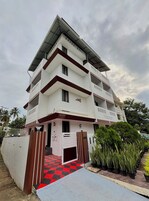 A multi-story building with a flat roof, balconies, and a gated entrance.