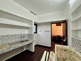 A kitchen with a tiled backsplash, a sink, and a window. There is a dining area with a table and chairs visible through an open door.