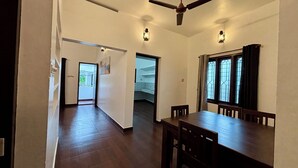 A spacious dining area with a high ceiling fan, wooden dining table, and chairs. There are two doors leading to other rooms. - Fort Grande Stay  (Kochi)