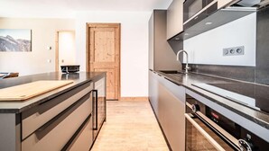 A modern kitchen with a wooden door, a black countertop, and stainless steel appliances. - 100m from resort center, 2nd floor, view village, terrace, tv, 84m², Morzine (Morzine)