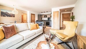 A modern living room with a sofa, armchair, and a dining area with a table and chairs. - 100m from resort center, 2nd floor, view village, terrace, tv, 84m², Morzine (Morzine)