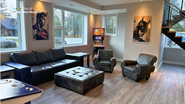 Een moderne woonkamer met een leren bank, twee fauteuils, een salontafel en een gameconsole.