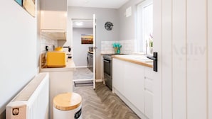 A modern kitchen with white cabinets, a yellow countertop, and a wooden floor.