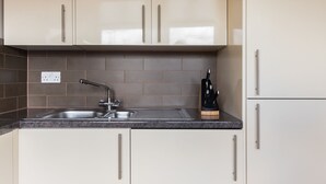 A kitchen with beige cabinets, a stainless steel sink, and a knife block.
